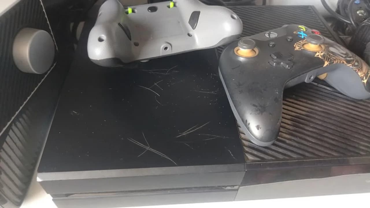Used black Xbox One with scratches and two worn controllers