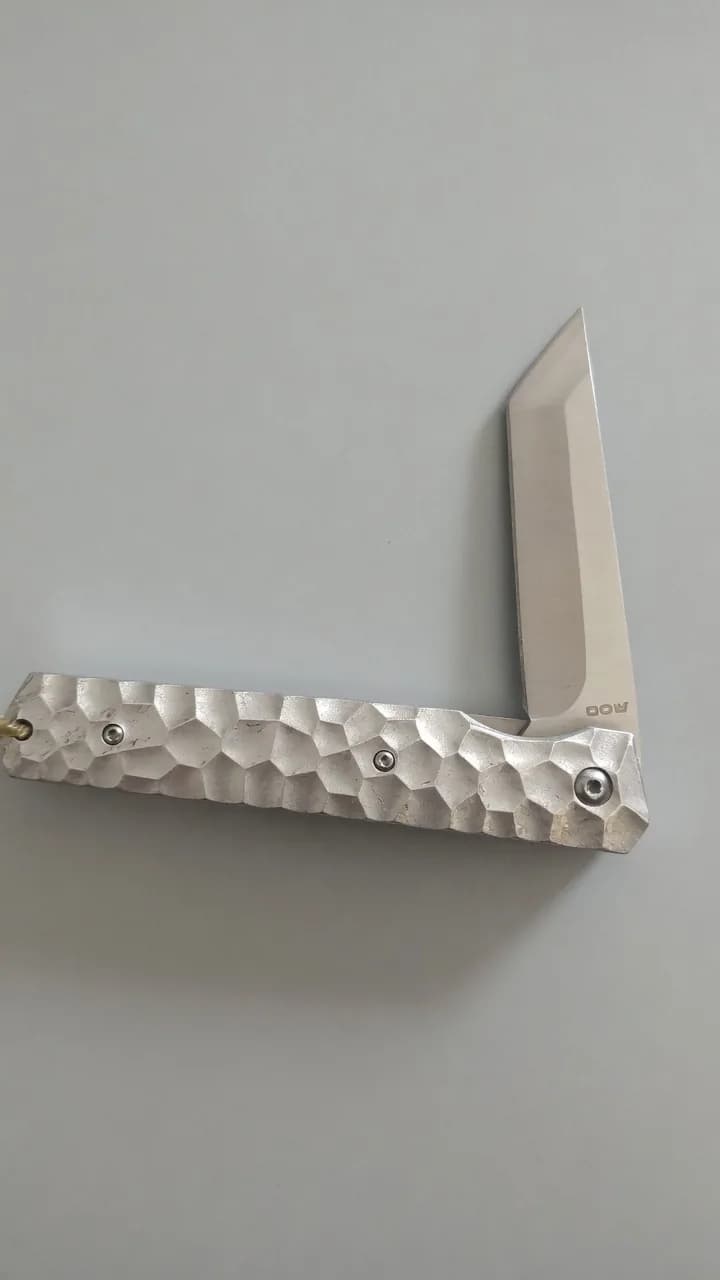 Open used silver folding knife with a textured handle