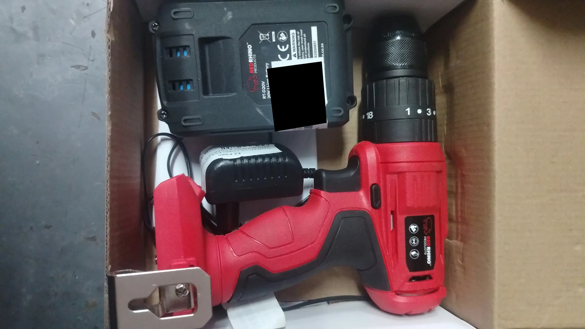 Red Rhino cordless drill, battery and charger in an open box