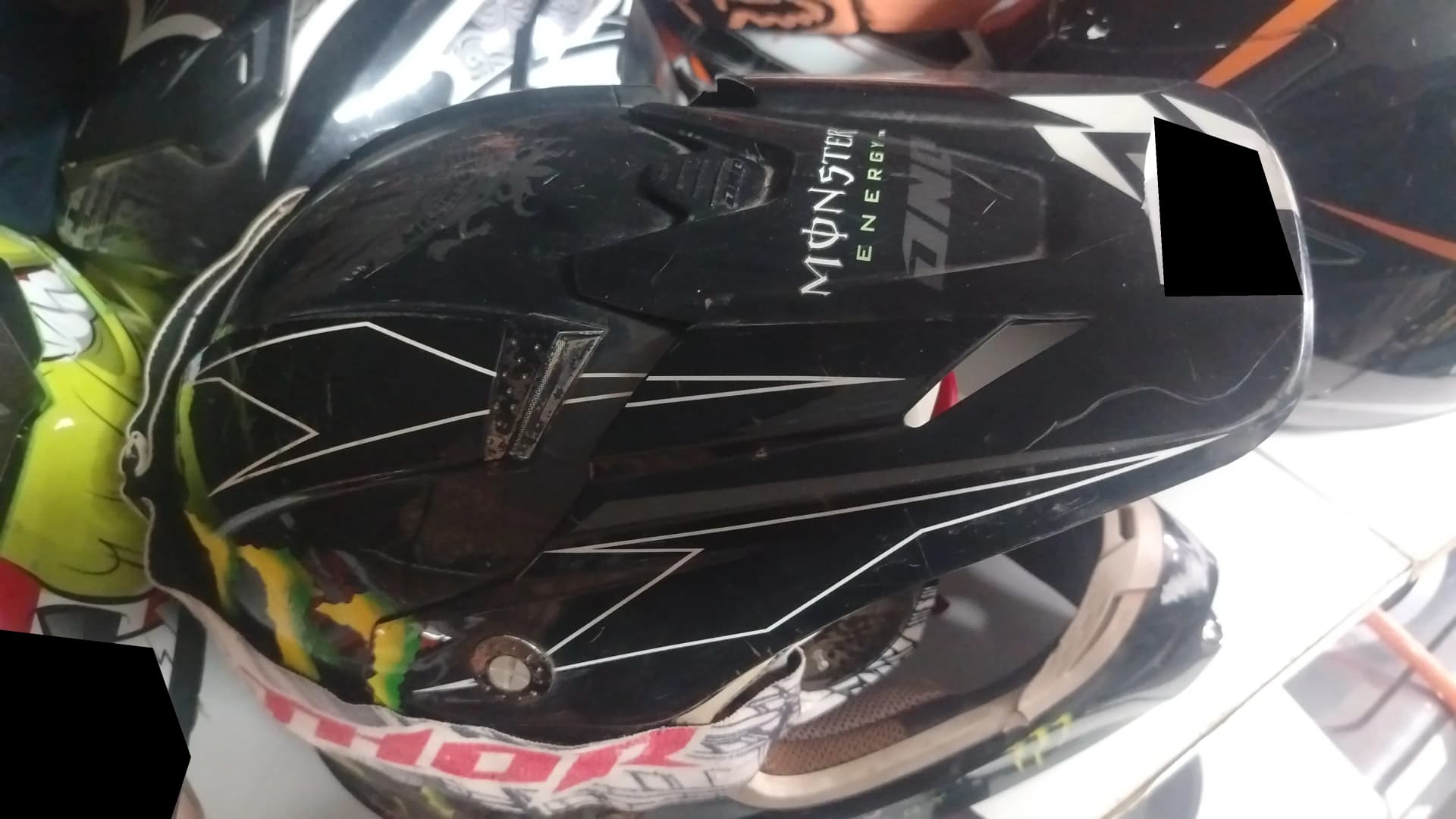 Used black off-road motorcycle helmet with a scratched peak