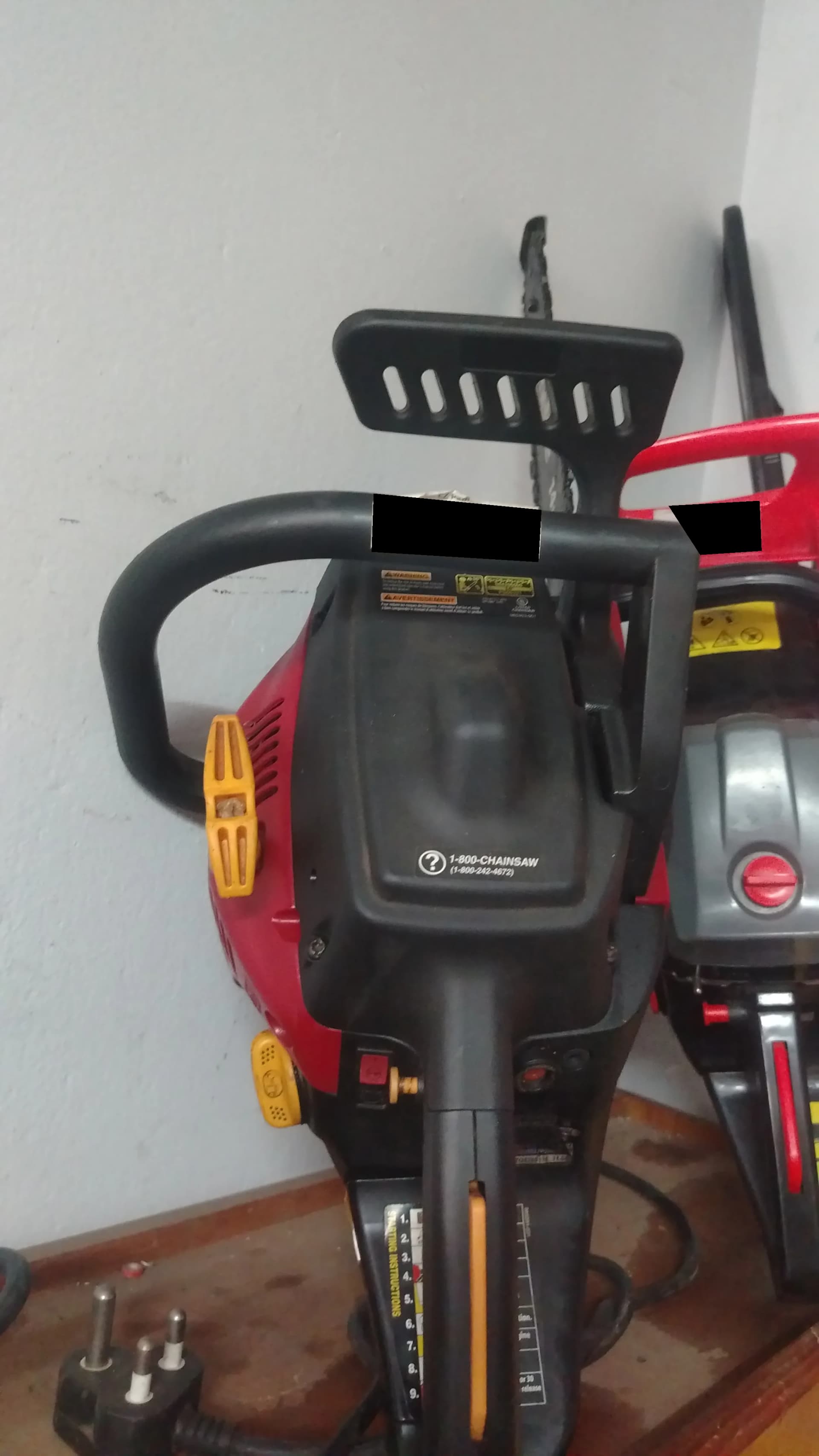 Rear of a used red petrol chainsaw